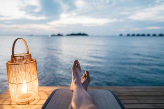 Person sitting on dock staring out at water.